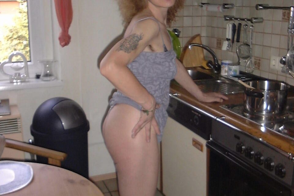 tätowierte reife Frau leichtbekleidet in der Küche